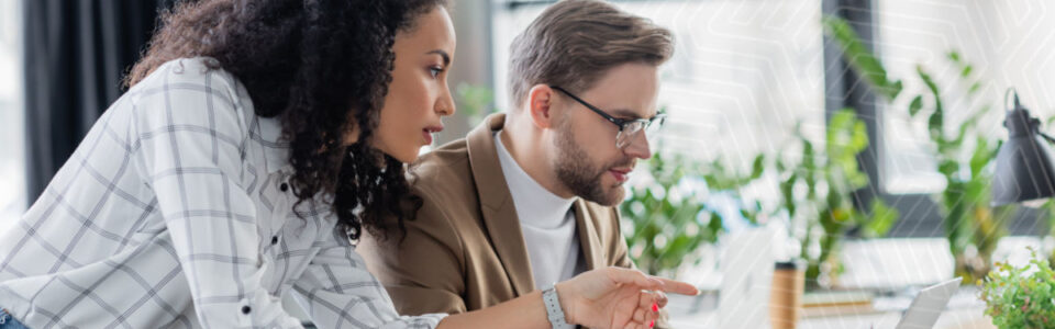 business woman pointing at laptop computer with colleague in office using contract lifecycle management software