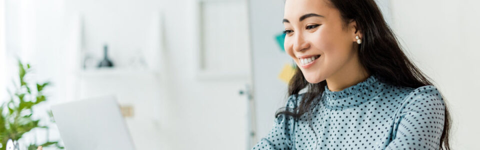 smiling businesswoman sitting at desk and using contract management software for contract redlining in office