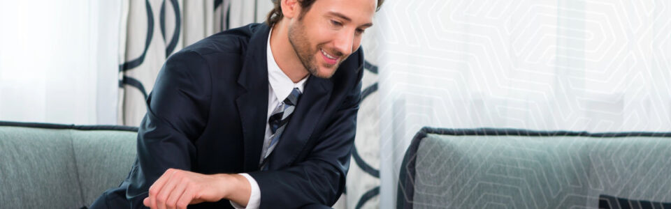 businessman smiles while using business contract management software on his laptop computer