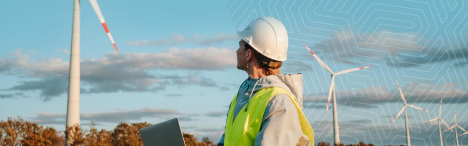 Woman holds a laptop to navigate contract management software for energy as she looks toward wind turbines