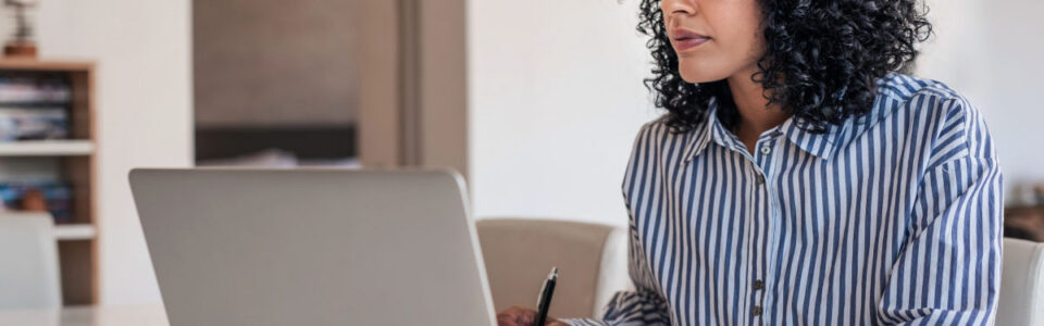 female business owner sits at desk and uses laptop computer to use mid-sized business contract software