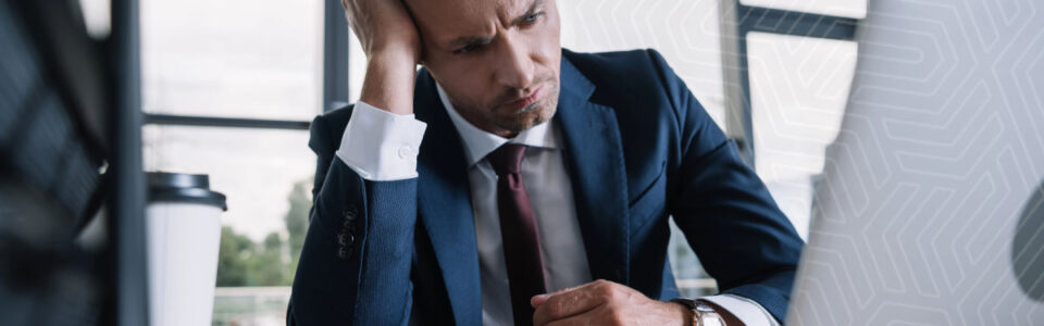 frustrated businessman stares at computer screen after falling victim to common Pitfalls in Contract Lifecycle Management